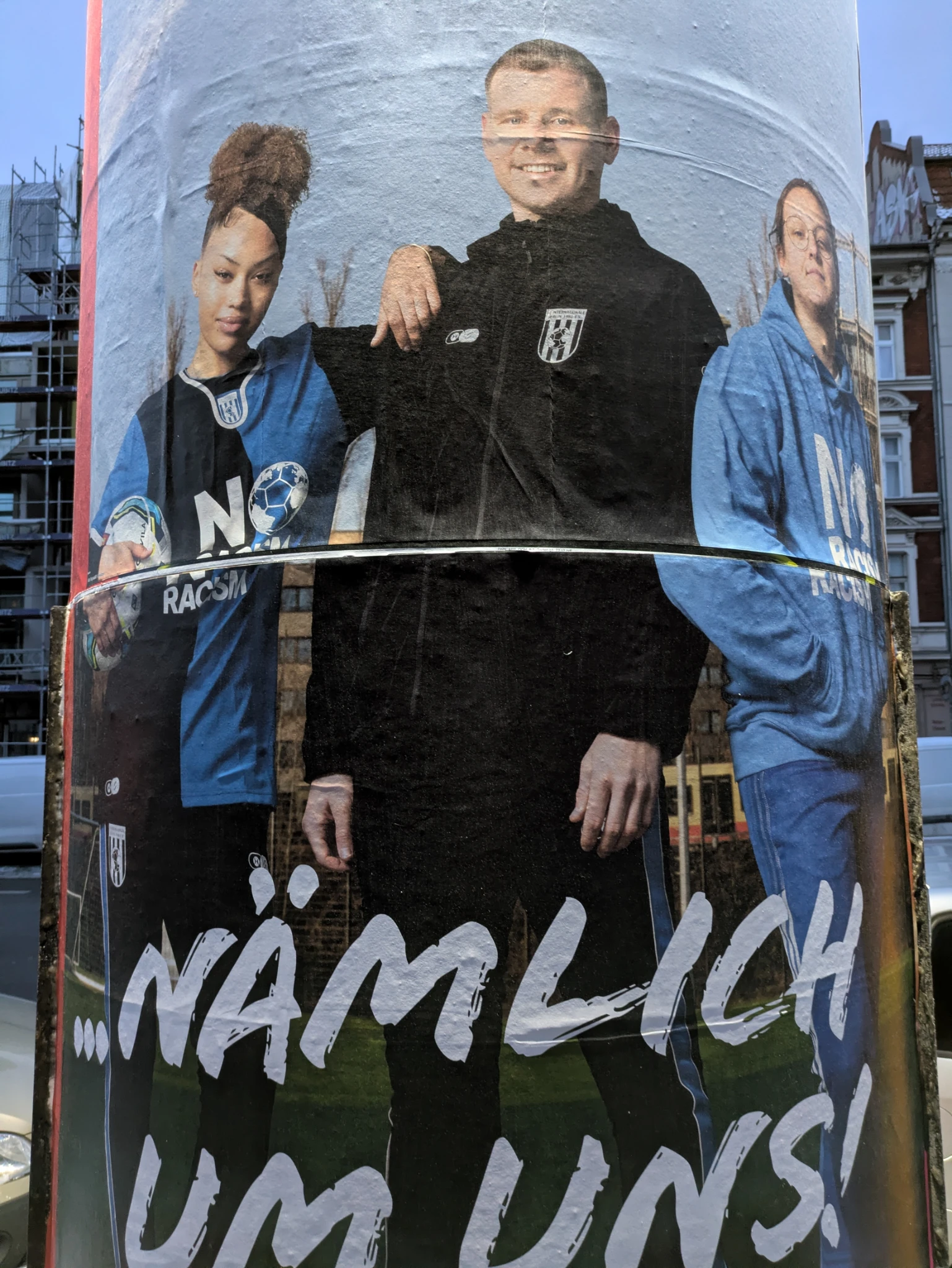 plakat auf einer Litfaßsäule, 3 personen in sportlichem outfit lächeln uns entgegen, darunter steht 

NÄMLICH UMS UNS!

das plakat ist nicht bündig geklebt, sodass die körper leicht verschoben wirken.