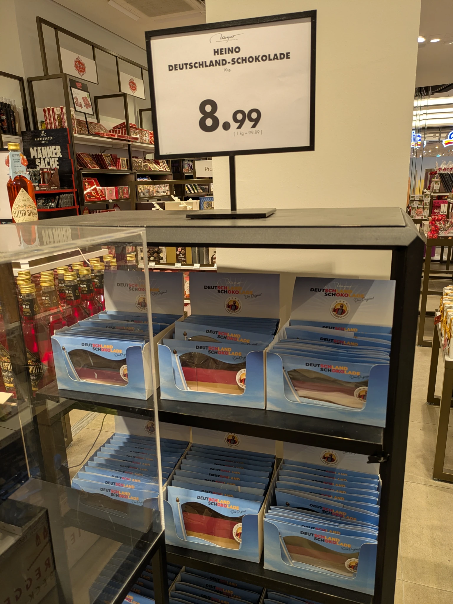 ein aufsteller in einem laden, ein schild sagt 

Heino
Deutschlandschokolade
8,99 €

Darunter mehrere hellblaue Verpackungen mit schwarzrotgelber schokolade.