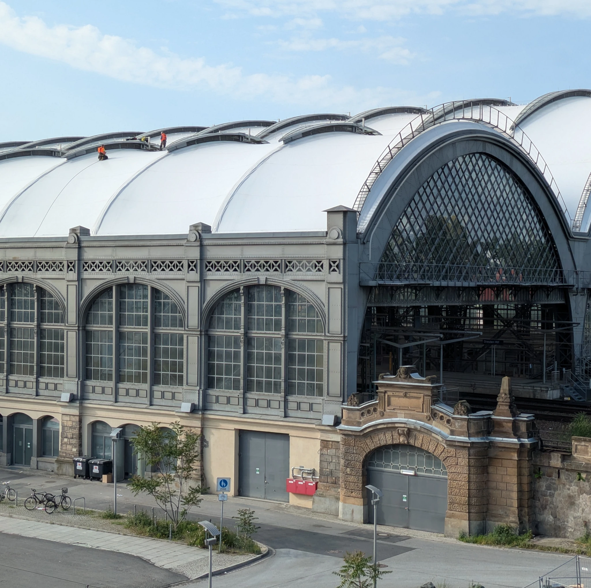 Bahnhofsgebäude mit weißem dach auf dem ganz winzige arbeiter arbeiten