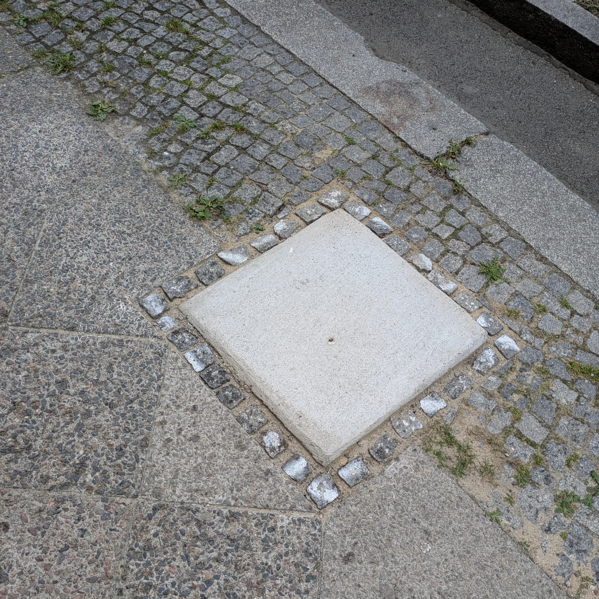 blick auf einen gehsteig, in der bildmitte eine quadratische platte 